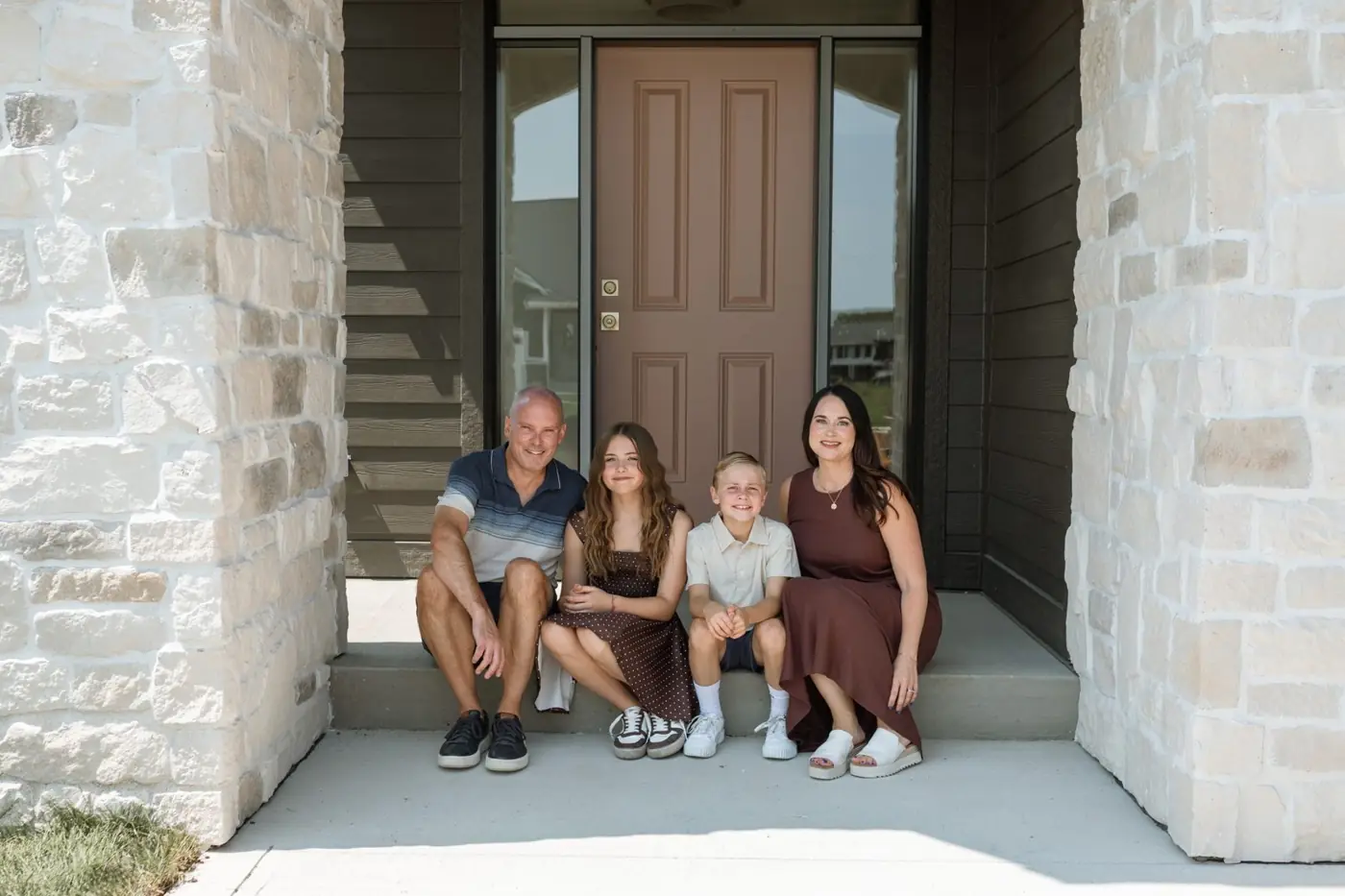 Kalen and Kurt Ludwig with Jules and Wells on the front step of The Noelle, their custom home
