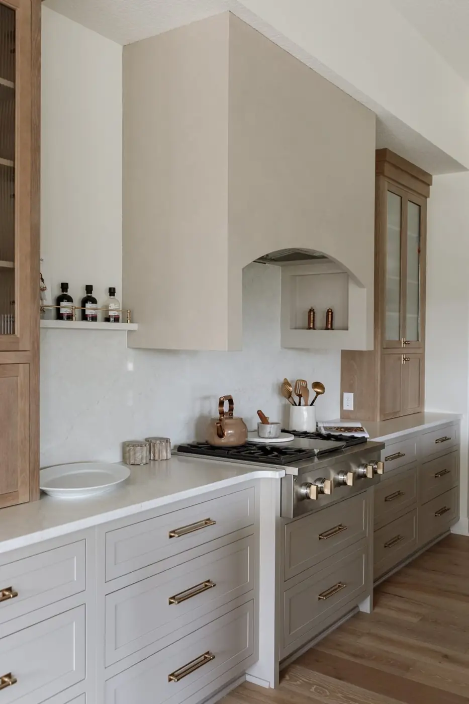 Plaster range hood with an inset spice niche above a professional gas range and white oak cabinetry