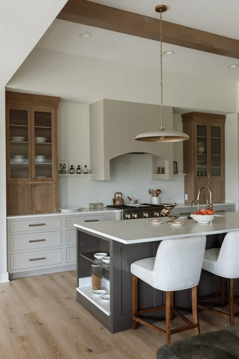 Kitchen island with upholstered stools and an open quartz-lined cat feeding station built into its end