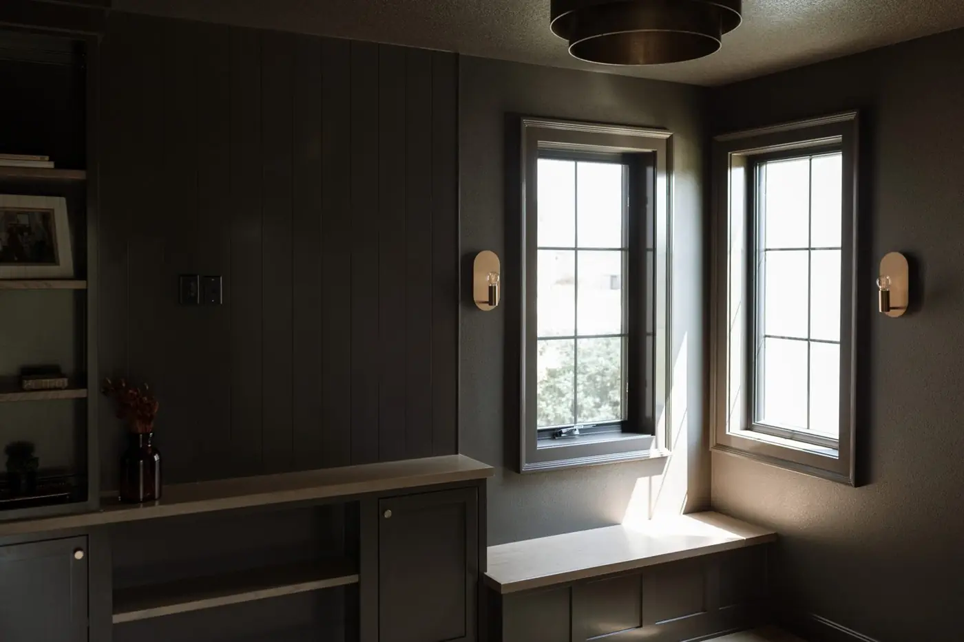 Kurt Ludwig's office with dark paneled walls, built-in cabinetry, brass sconces and a corner window seat