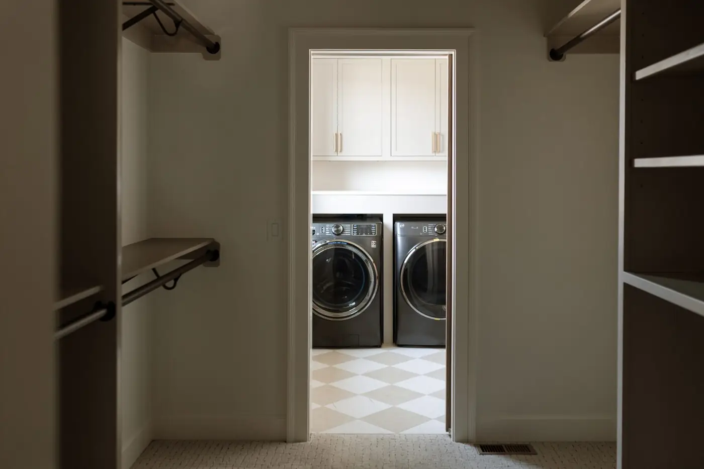 Primary walk-in closet opening directly into the laundry room with a checkered tile floor