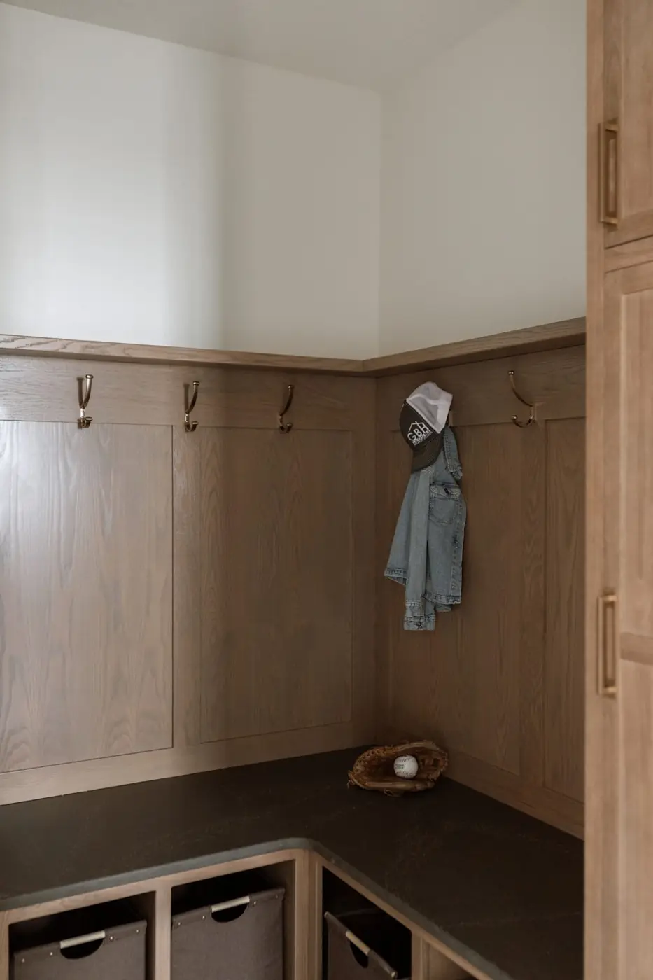 White oak mudroom lockers with hooks, a bench and storage baskets