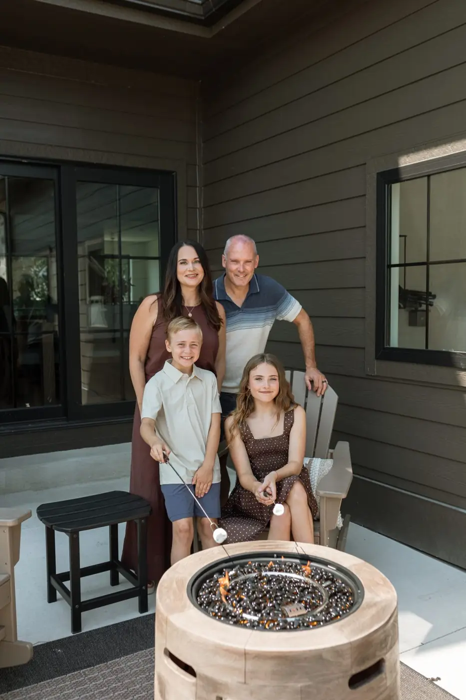 The Ludwig family roasting marshmallows around a fire table outside their home