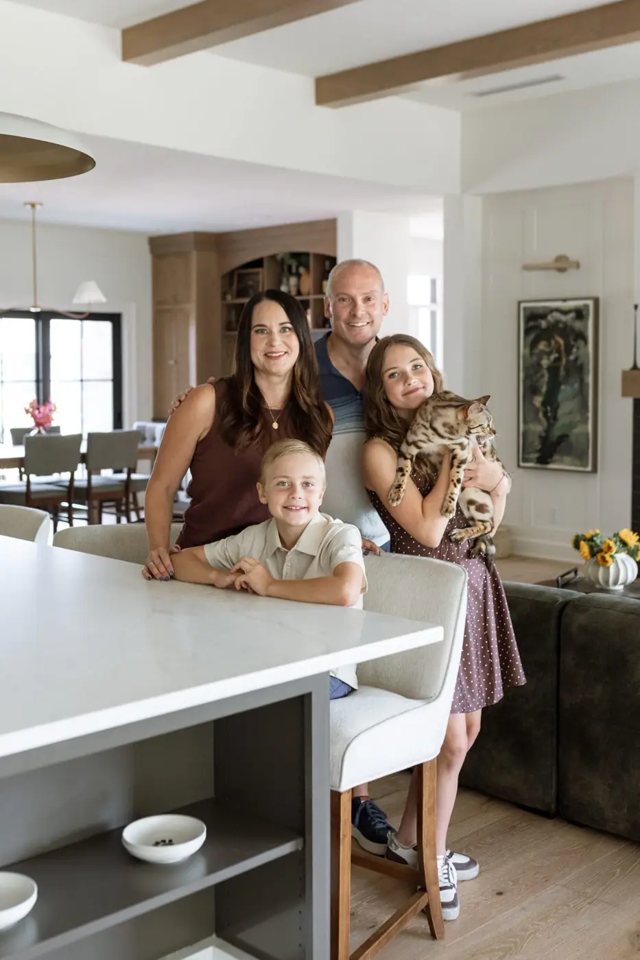 The Ludwig family gathered at the kitchen island in The Noelle holding Reese the cat